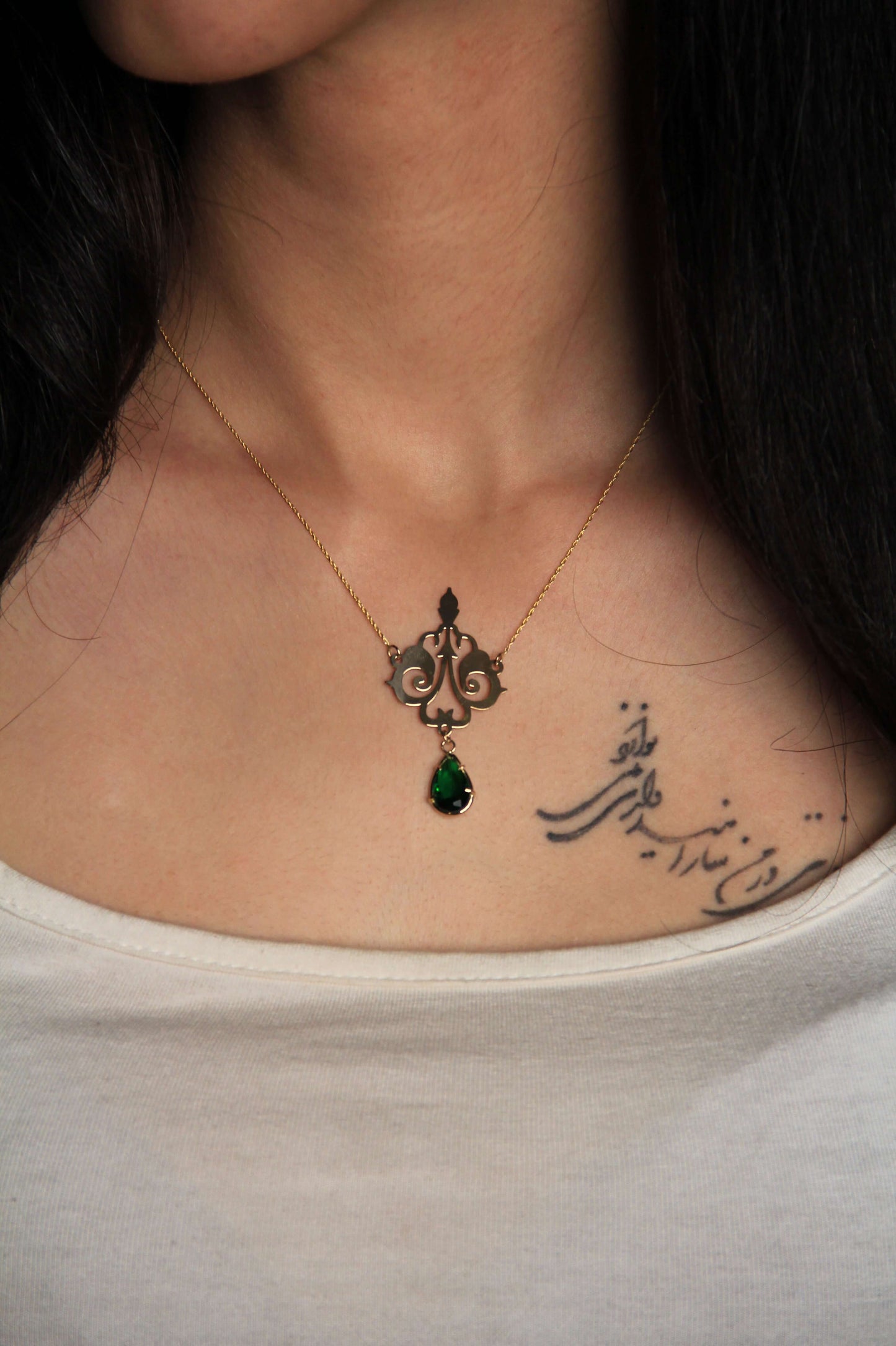 Oriental Design Gold Necklace featuring a green gemstone on a woman, showcasing eastern elegance and culture.