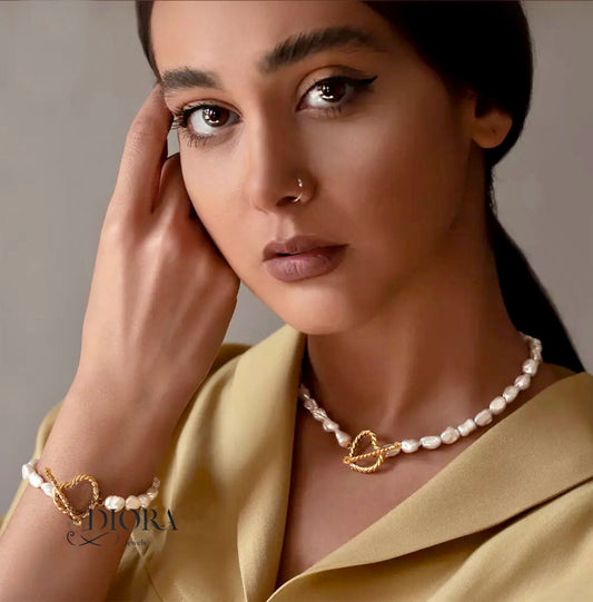 A woman wearing a golden baroque-style necklace with heart-shaped pendants.