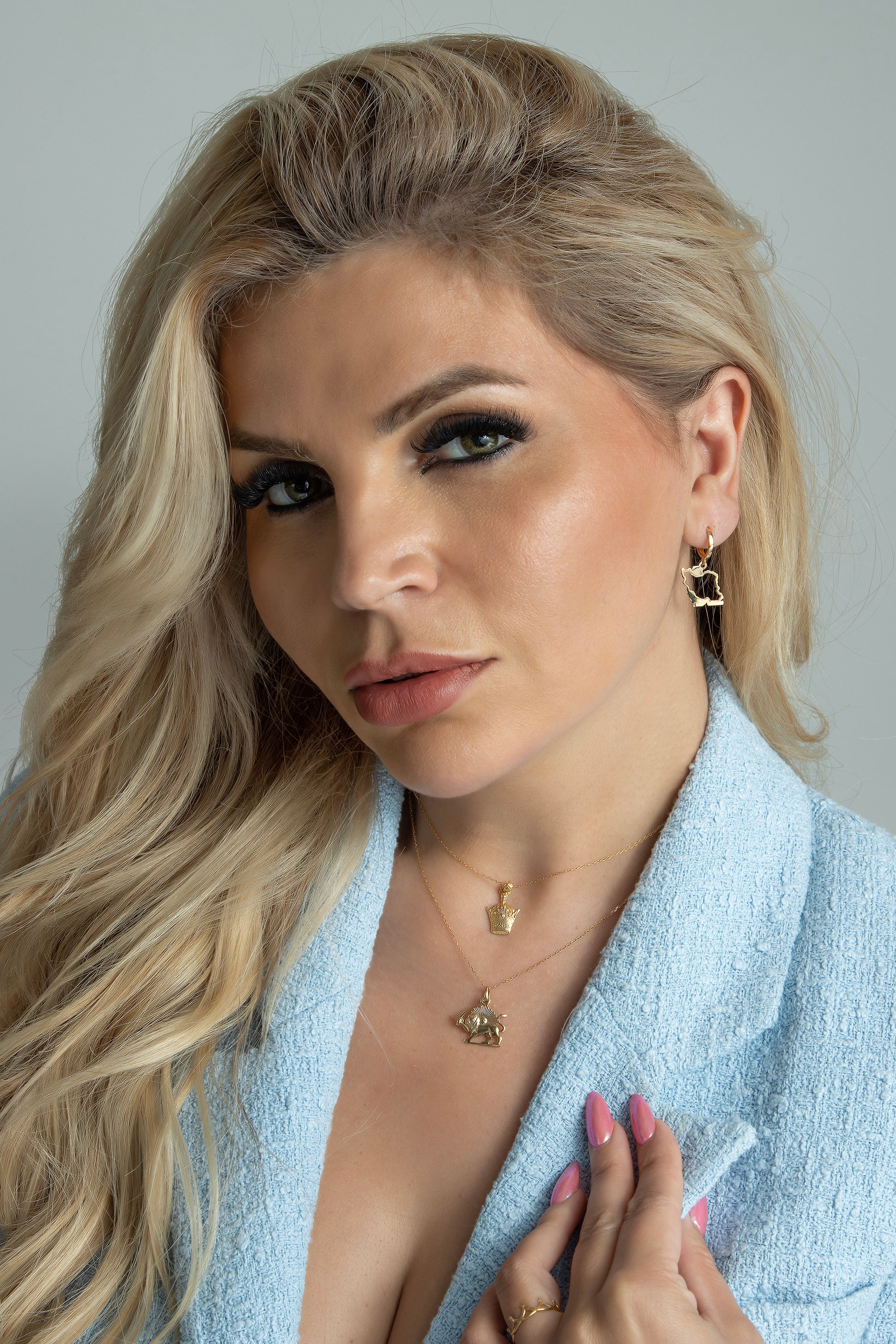 A person wearing the Shir & Khoorshid Pendant with a gold color and chain necklace.