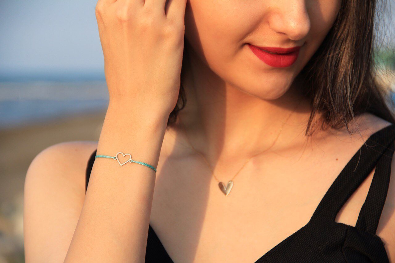 Minimal Heart Bracelet worn by a woman, showcasing its delicate design and elegant appeal at the beach.