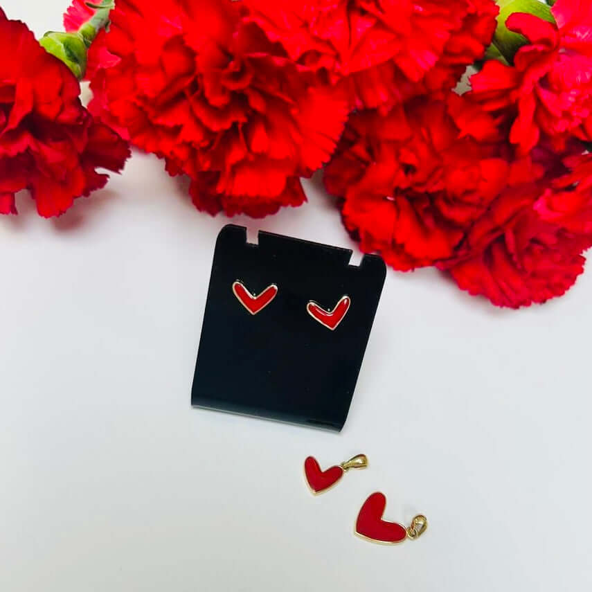 Red heart-shaped earrings with gold accents on a white background with red flowers.