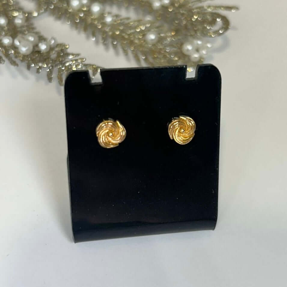 Gold spiral earrings on a black earring stand with a white background