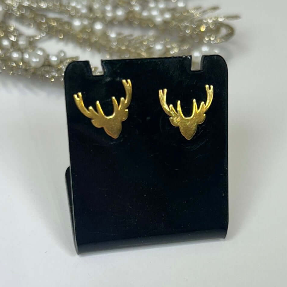 Gold deer antler earrings on a black stand with a white background