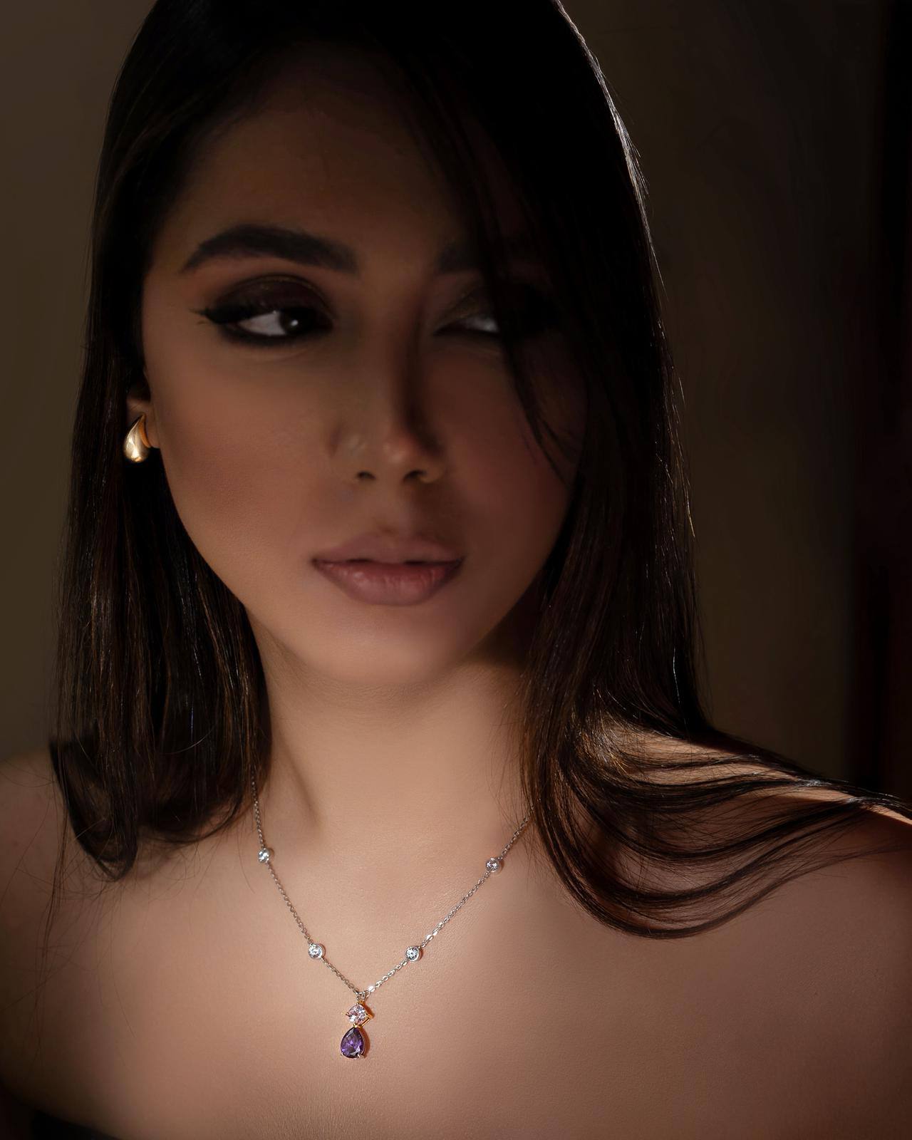 Woman wearing a necklace with a dark background