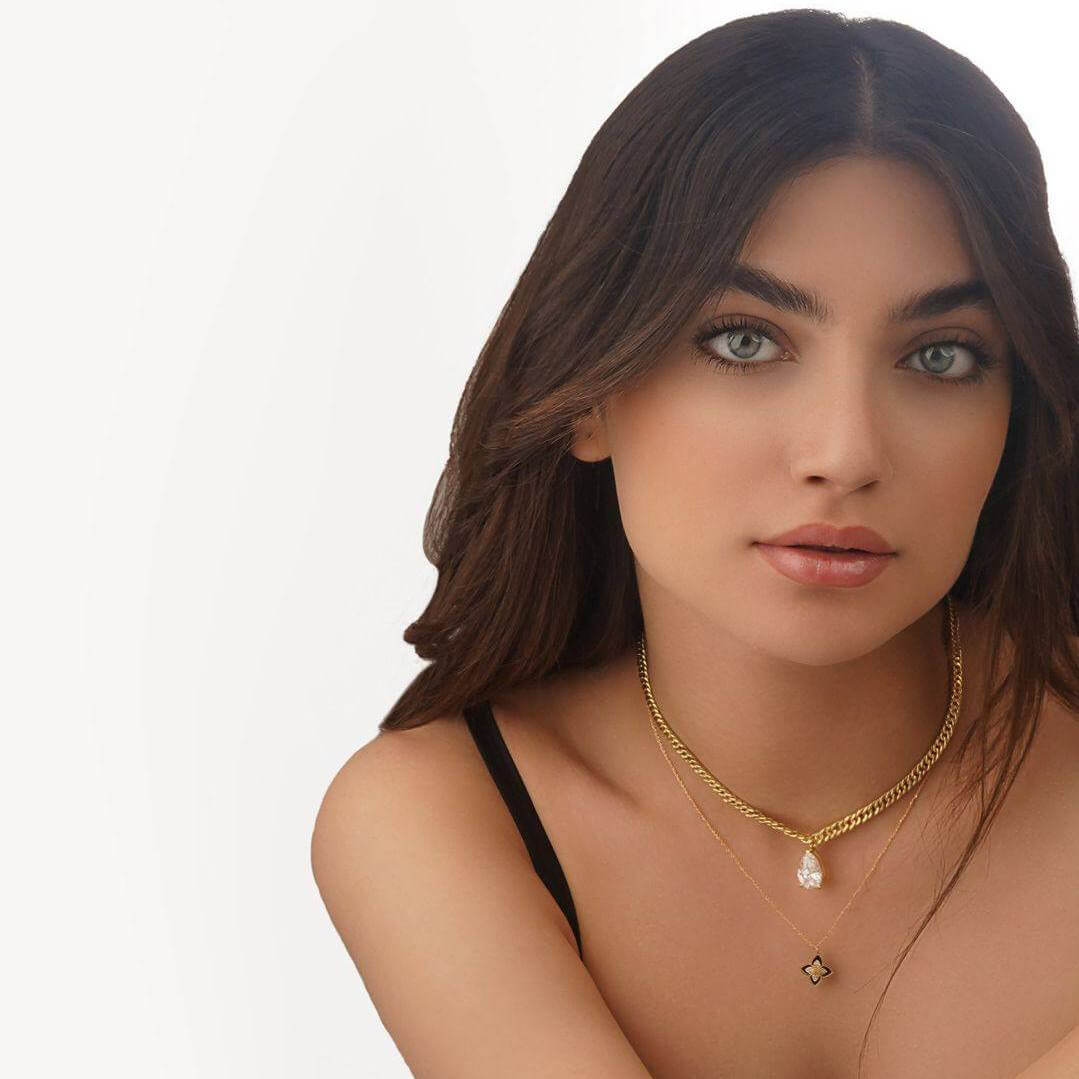 Woman wearing a gold necklace with a pendant on a white background