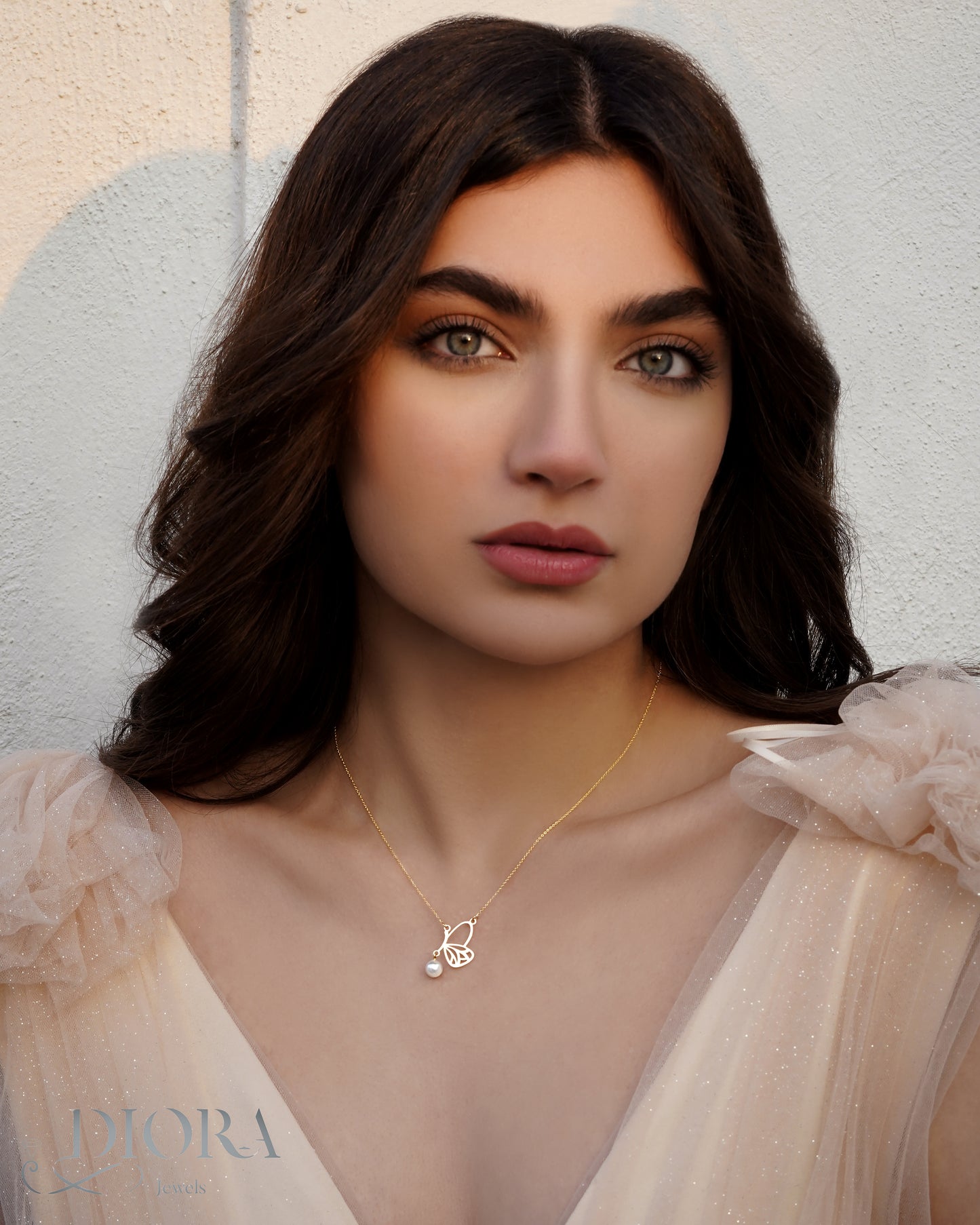 A woman wearing a minimal butterfly necklace in gold.