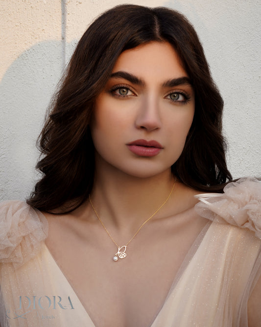 A woman wearing a minimal butterfly necklace in gold.