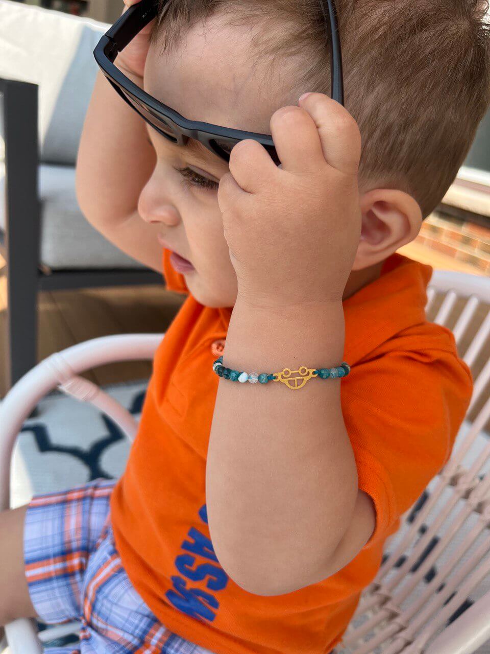 Mini Car Kid's Bracelet worn by a young boy, showcasing the vibrant colors and 18K gold design.