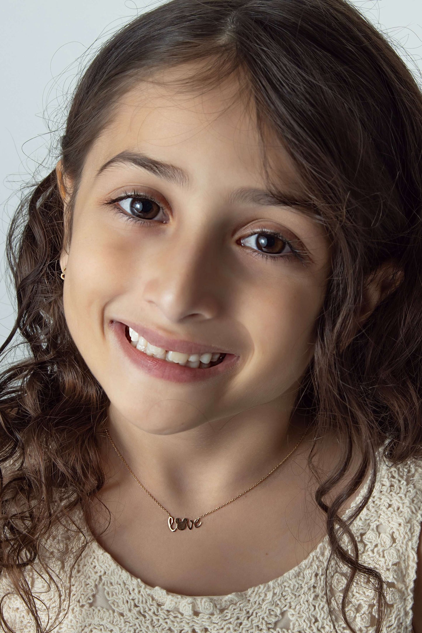 Micky Love Necklace worn by a smiling girl with curly hair, showcasing its charm and sparkle.