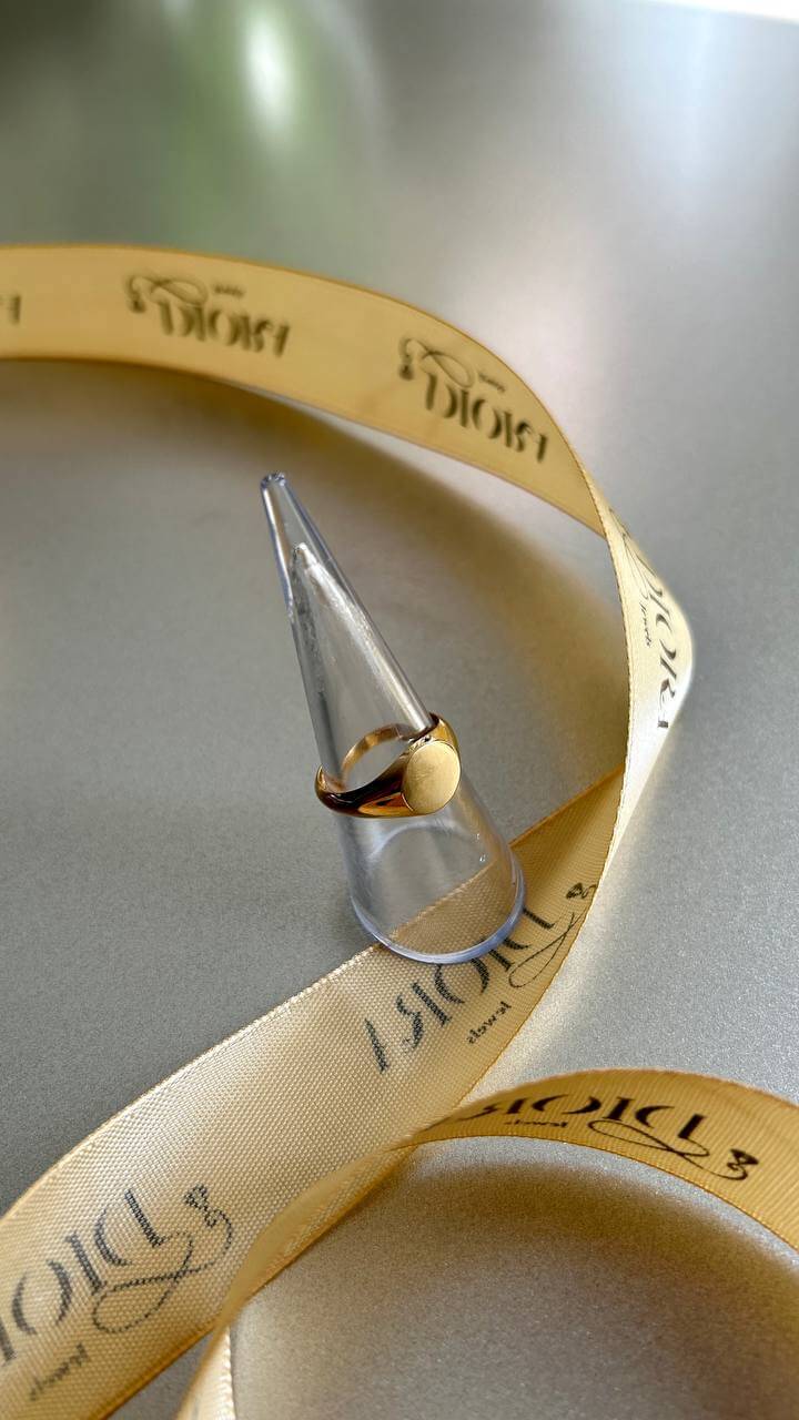 Circle Signed Ring displayed elegantly on a ring holder beside golden ribbon for luxurious presentation.