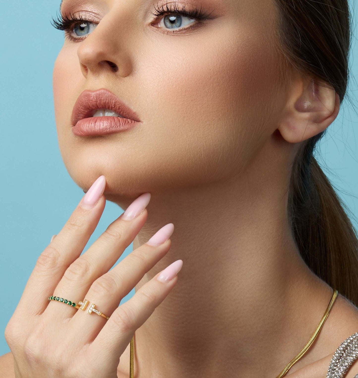 Close-up of a model showcasing the Amara Eternity Ring in 18K gold with pink nails and elegant makeup.