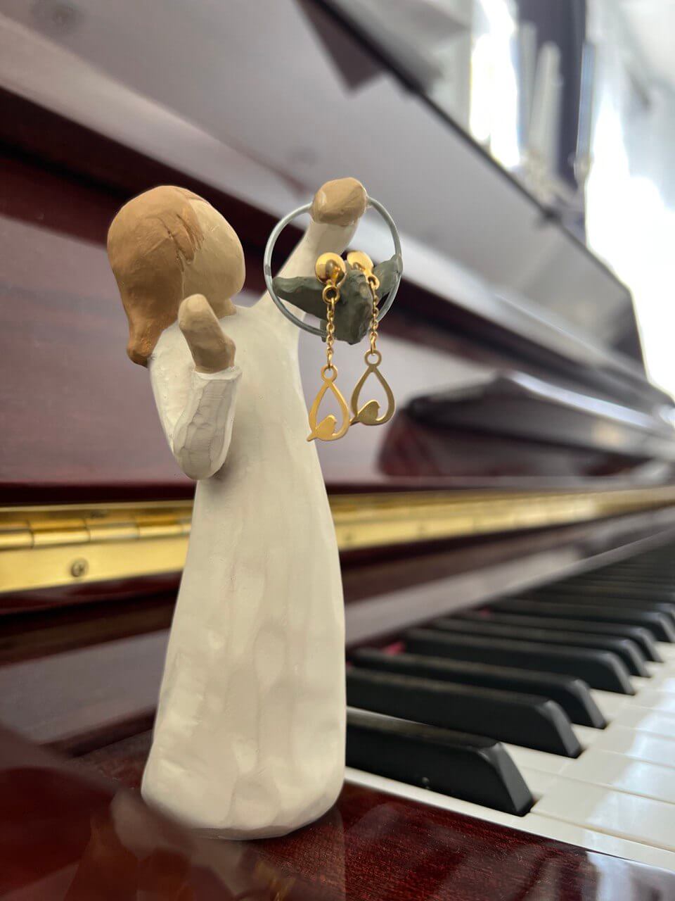 Love Birds Earing displayed on a figurine next to a piano, showcasing 18K Solid Gold design.
