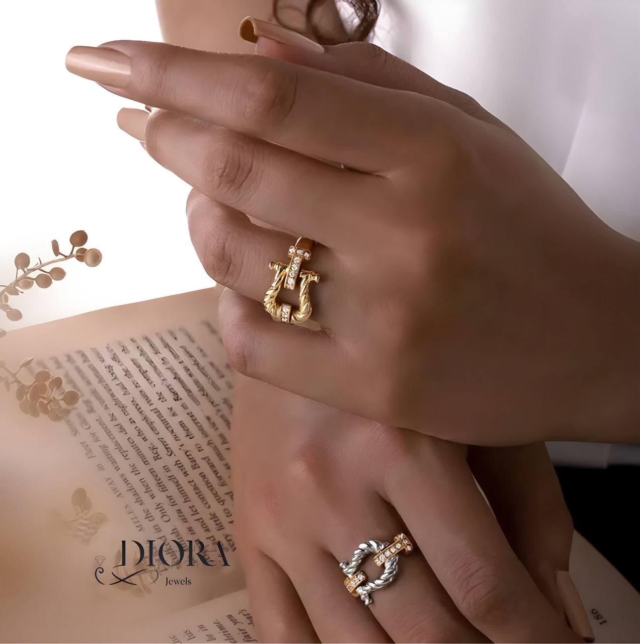 Close-up of hands wearing gold rings with a Dior branded book in the background