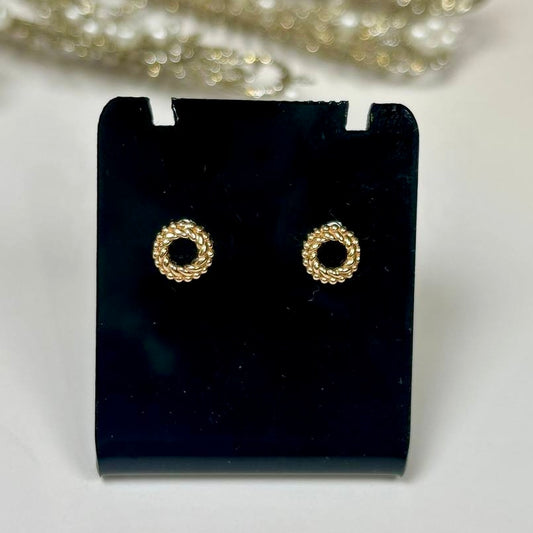 Gold hoop earrings on a black earring stand with pearls in the background