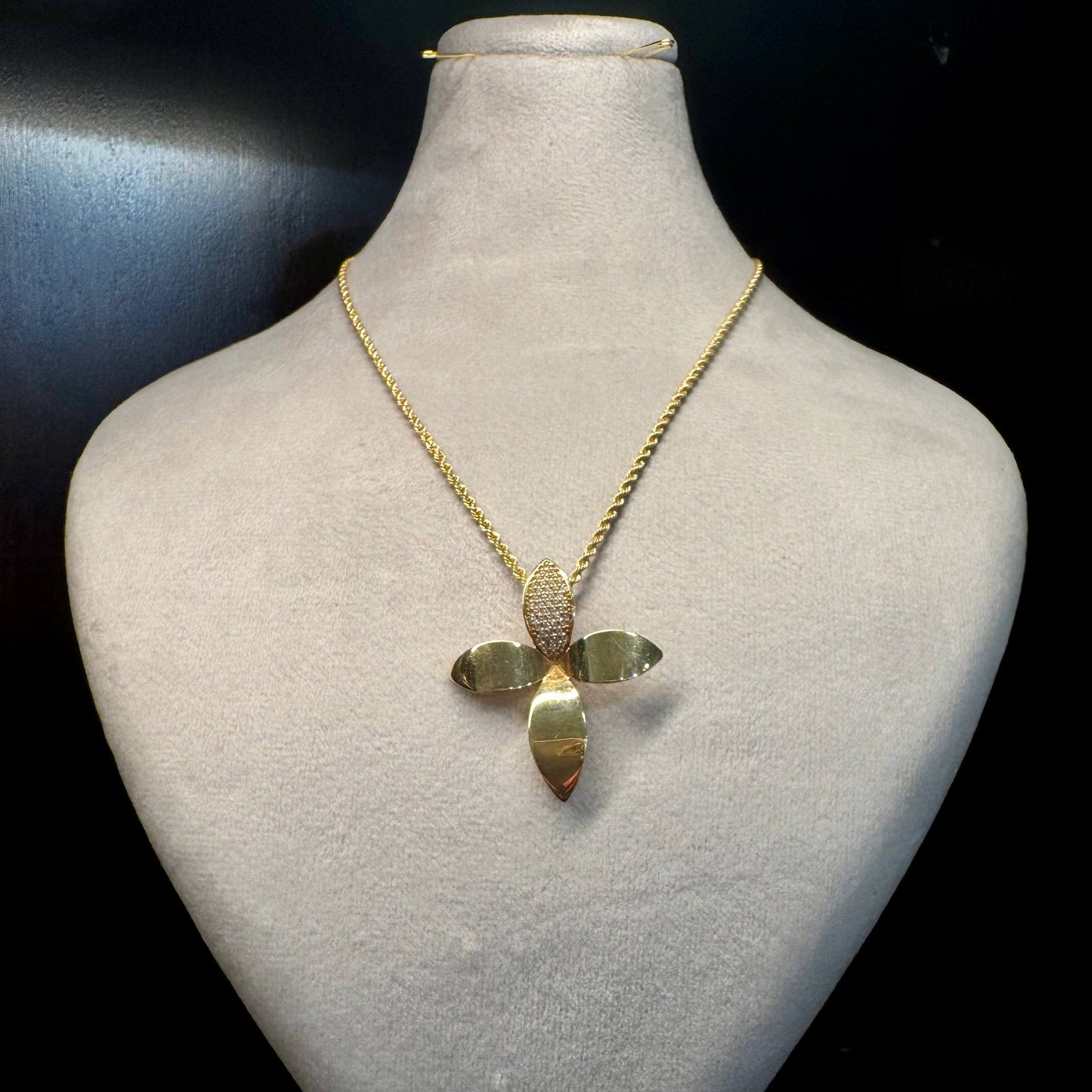 Gold necklace with a pendant on a mannequin bust against a black background